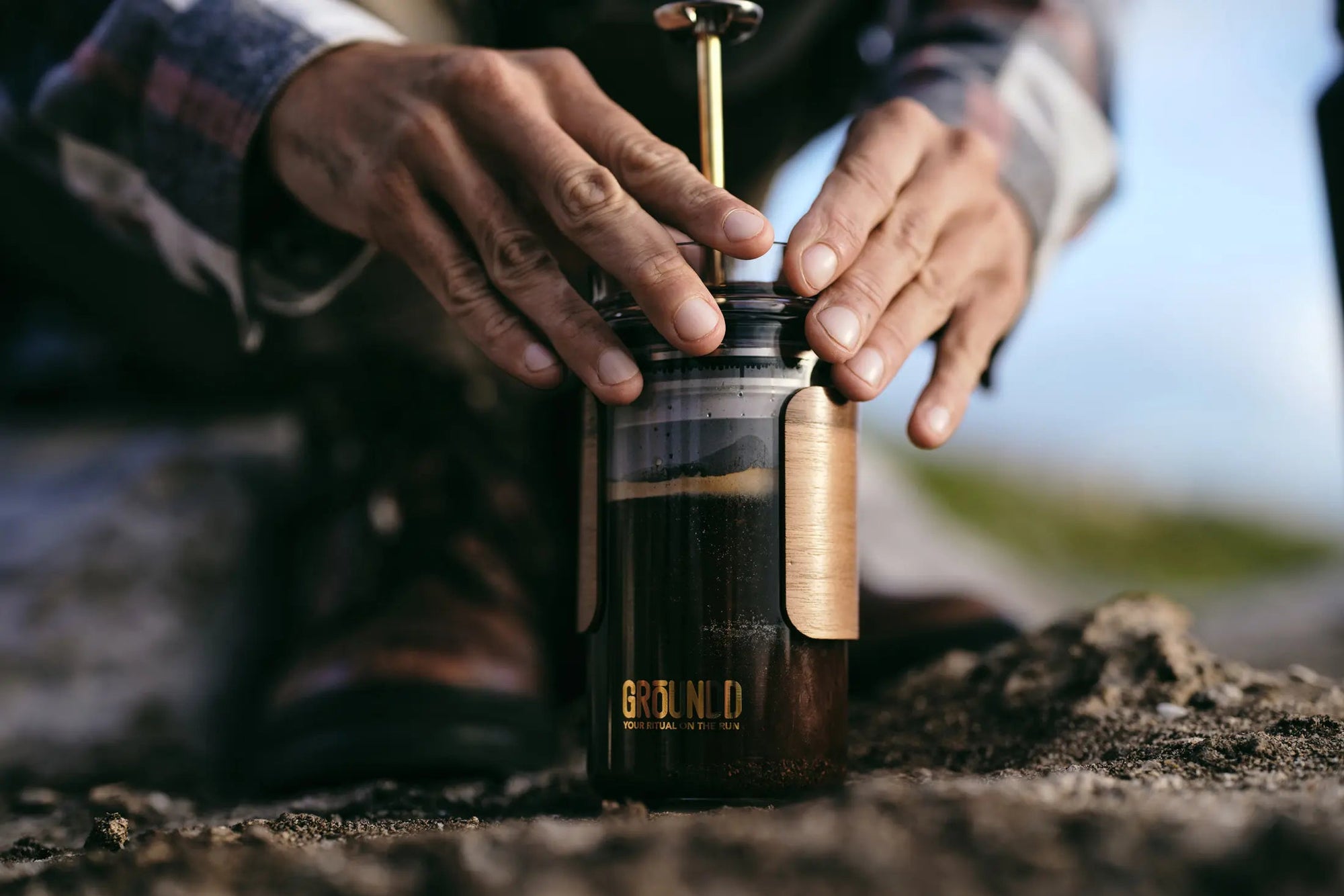 Person using a manual coffee grinder outdoors