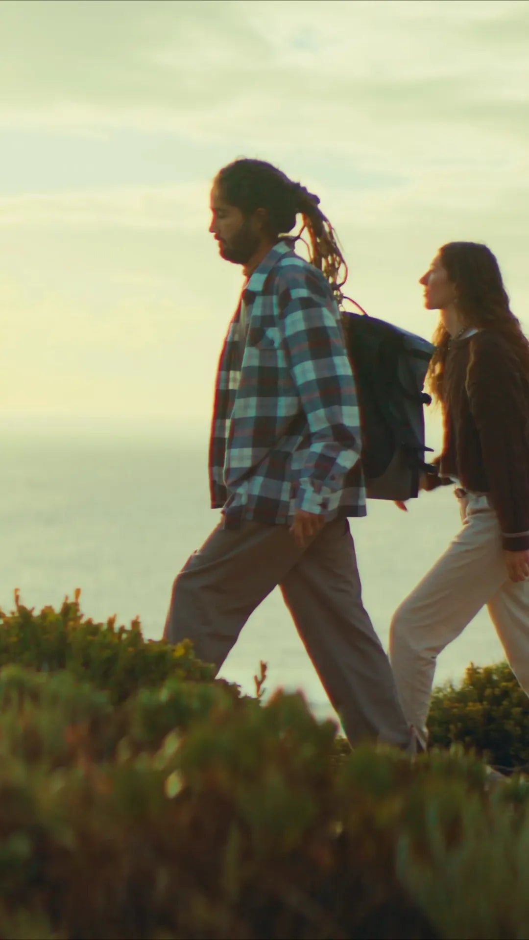 Two people walking a coastal headland at sunset