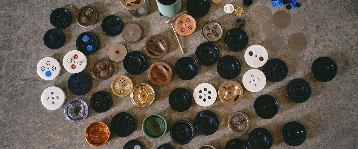 Dozens of GROUNDD prototype lids and components laid out on a concrete floor