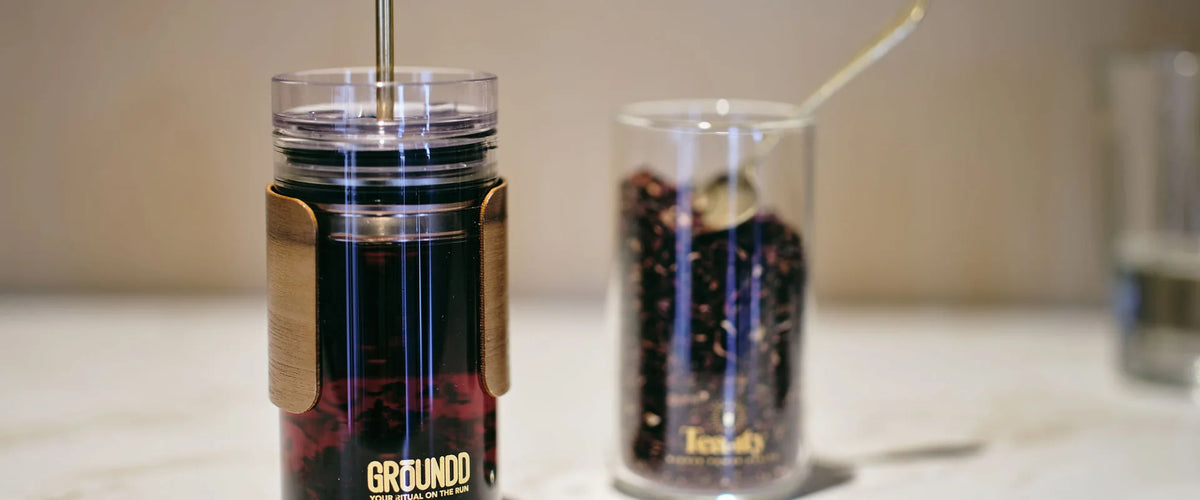 A GROUNDD xpress of coffee beside a jar of loose leaf tea on a marble bench