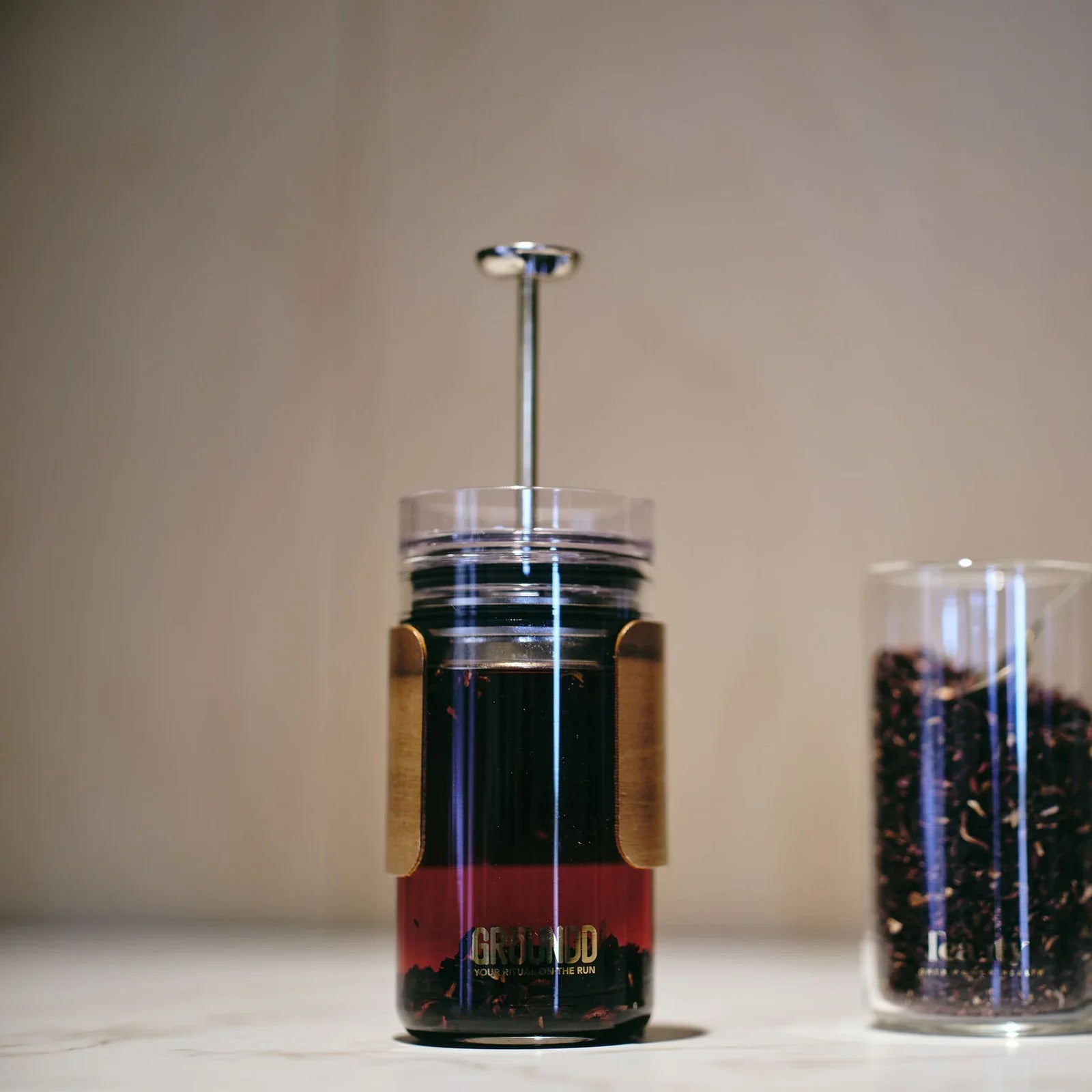 The GROUNDD xpress brewing coffee beside a jar of loose leaf tea