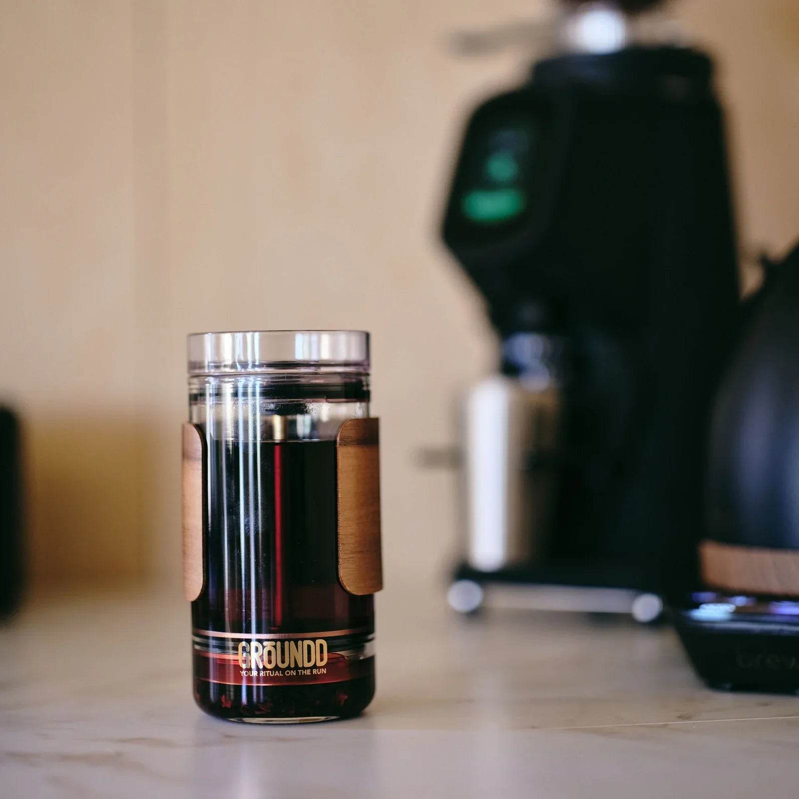 The GROUNDD xpress full of coffee on a cafe bench beside a grinder