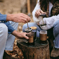 Two GROUNDD xpress cups being brewed on a tree stump at camp