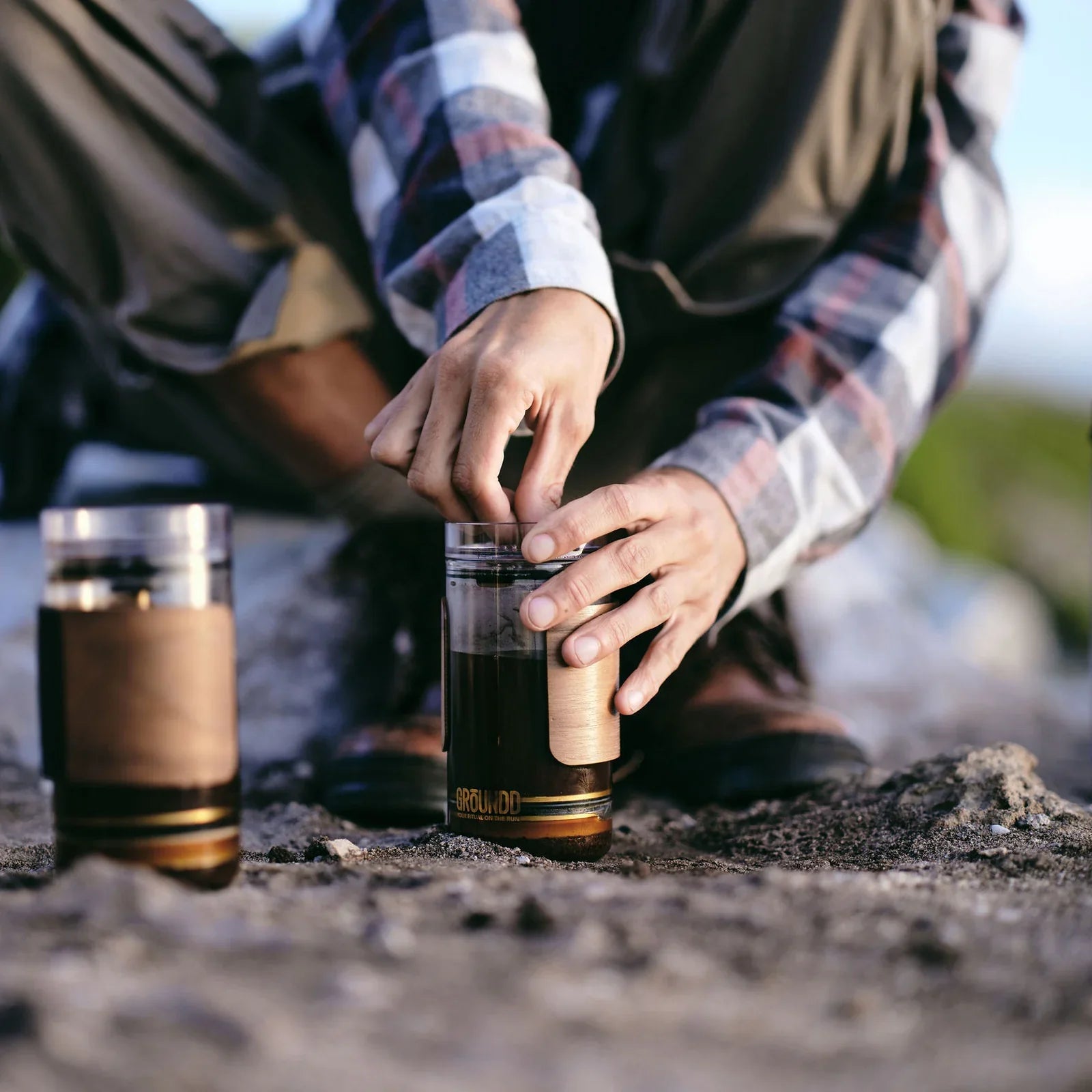 Two GROUNDD xpress cups brewing on a coastal rock